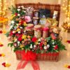 Wicker Diwali gift hamper with protein bars, Maamoul cookies, Ferrero Rocher and potpourri, edged with fresh flowers and a red bow