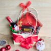 Christmas-themed gift bag with wine, Lindt chocolates, Hershey’s dark chocolate, pinecones, and red ribbon.