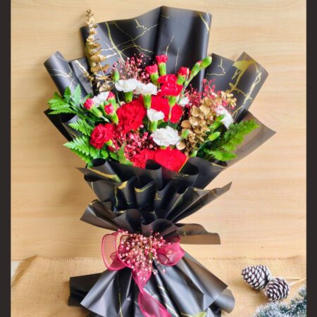 Christmas-themed bouquet with red carnations, white flowers, greens, and gold accents in black wrapping.