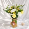 Mother’s Day yellow and white fresh flower arrangement in glass vase with roses, carnations and eucalyptus by local florist