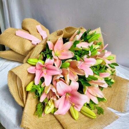 Pink lily bouquet wrapped in jute with green foliage – perfect for birthday gifts, anniversary flowers, and same day flower delivery in Bengaluru.