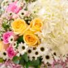 A pastel floral arrangement in a glass vase featuring white hydrangeas, yellow and pink roses, white daisies, and pink fillers, tied with a white ribbon, ideal for same day flower delivery in Bangalore
