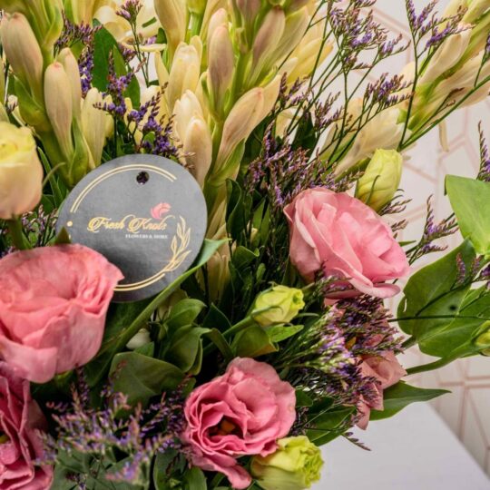 Vase arrangement featuring eustoma, tuberose, and mixed greens in a clear glass vase.