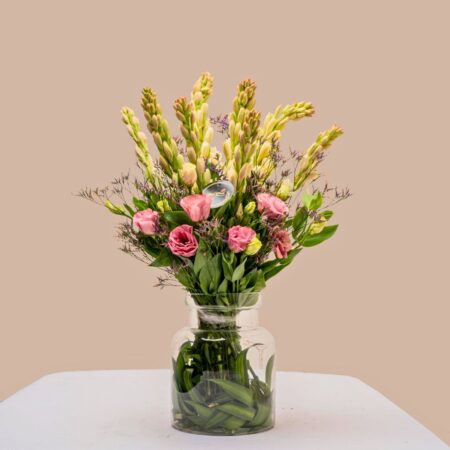 Vase arrangement featuring eustoma, tuberose, and mixed greens in a clear glass vase.
