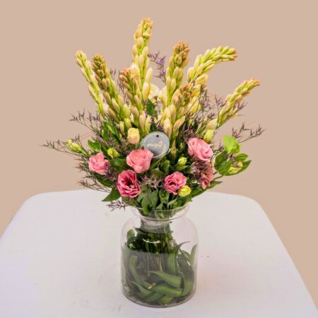 Vase arrangement featuring eustoma, tuberose, and mixed greens in a clear glass vase.