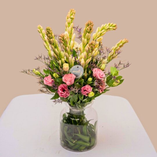 Vase arrangement featuring eustoma, tuberose, and mixed greens in a clear glass vase.