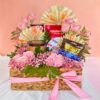 Gift hamper with chocolates, pink roses, baby’s breath, and a candle arranged in a woven basket with a pink ribbon