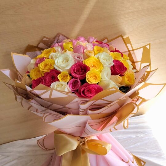 A vibrant mixed rose bouquet with pink, yellow, and white roses, elegantly wrapped in blush and gold paper with a satin bow — available for same day flower delivery in Bangalore.