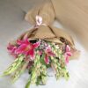 Fresh lily and rose bouquet wrapped in burlap, featuring pink lilies, white roses, and lush green buds.