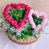 Heart-shaped red and pink rose arrangement in a basket with baby’s breath and greenery.