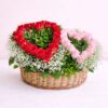 Heart-shaped red and pink rose arrangement in a basket with baby’s breath and greenery.