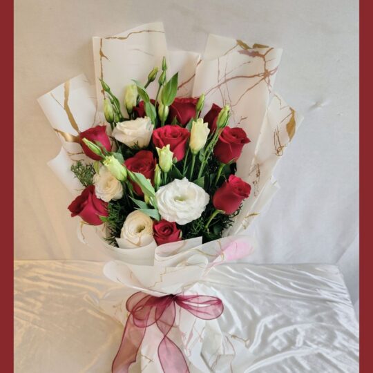 Red and white fresh flower bouquet of roses and eustoma (exotic flower) wrapped in marble paper with satin ribbon.