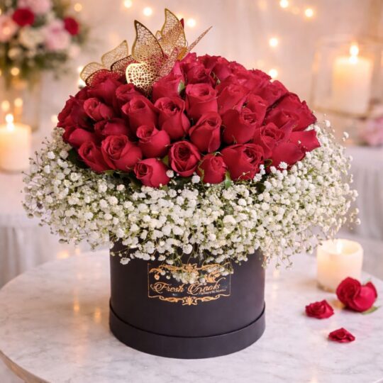 Black hatbox with a dome of red roses surrounded by baby’s breath and decorated with golden butterflies.