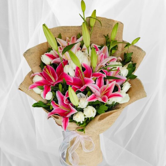 Fresh lily and rose bouquet wrapped in burlap, featuring pink lilies, white roses, and lush green buds.