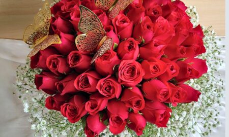 “Black hatbox with a dome of red roses surrounded by baby’s breath and decorated with golden butterflies.”