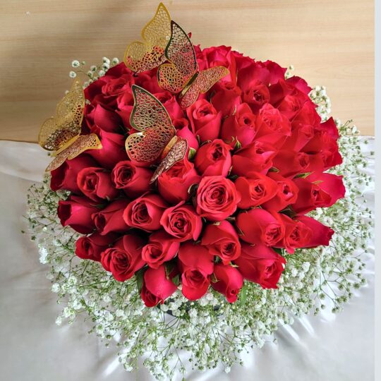 “Black hatbox with a dome of red roses surrounded by baby’s breath and decorated with golden butterflies.”