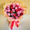 Handcrafted bouquet of red and pink roses wrapped in pink and gold paper with satin ribbon.