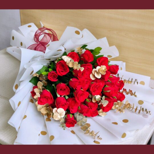 Red rose bouquet with golden accents and white polka-dot wrapping – premium romantic flowers by FreshKnots, same-day delivery in Bangalore.