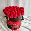 Red roses arranged in a black hatbox with a red ribbon, luxury rose box by Fresh Knots for gifting and same-day flower delivery in Bangalore.