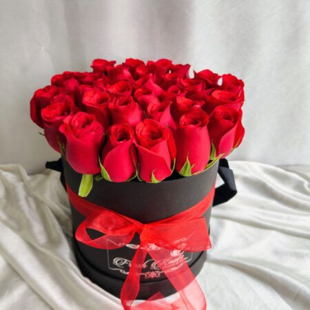 Red roses arranged in a black hatbox with a red ribbon, luxury rose box by Fresh Knots for gifting and same-day flower delivery in Bangalore.