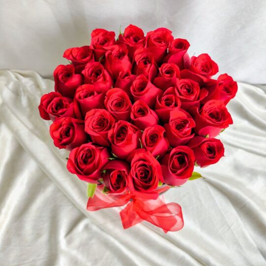 Red roses arranged in a black hatbox with a red ribbon, luxury rose box by Fresh Knots for gifting and same-day flower delivery in Bangalore.