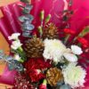 “Christmas flower bouquet with red and white flowers, gold pine cones, and winter greens, wrapped in burgundy and gold paper – FreshKnots Bangalore.”