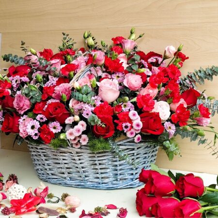 Luxury floral basket arrangement with red roses, pink roses, carnations, fillers and eucalyptus by FreshKnots Bangalore.