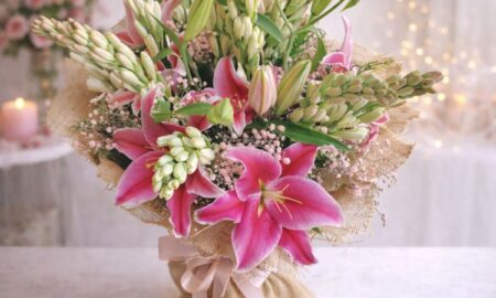 Fresh lily and rose bouquet wrapped in burlap, featuring pink lilies, white roses, and lush green buds.