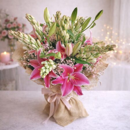 Fresh lily and rose bouquet wrapped in burlap, featuring pink lilies, white roses, and lush green buds.