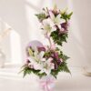 A pastel floral arrangement in a glass vase featuring white hydrangeas, yellow and pink roses, white daisies, and pink fillers, tied with a white ribbon - ideal for same day flower delivery in Bangalore.