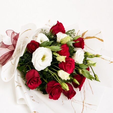 Red and white fresh flower bouquet of roses and eustoma (exotic flower) wrapped in marble paper with satin ribbon.