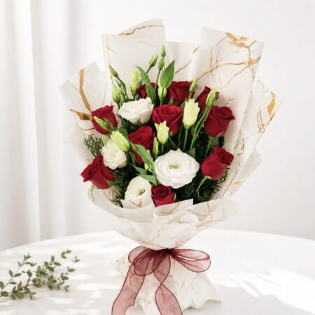 Red and white fresh flower bouquet of roses and eustoma (exotic flower) wrapped in marble paper with satin ribbon.