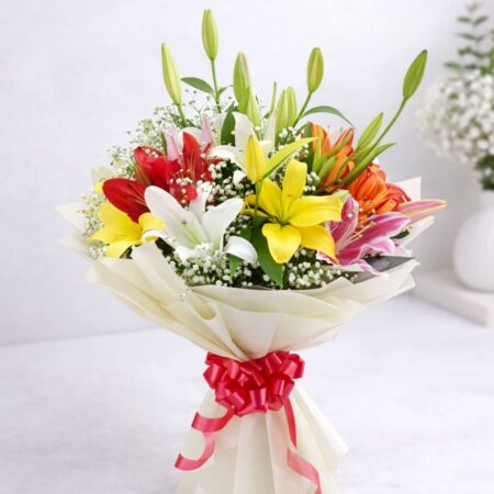 Colourful bouquet of Asiatic and Oriental lilies with baby’s breath wrapped in cream paper with red ribbon