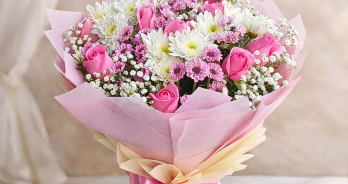 Pink rose and white chrysanthemum bouquet with baby’s breath wrapped in blush pink paper and satin ribbon.