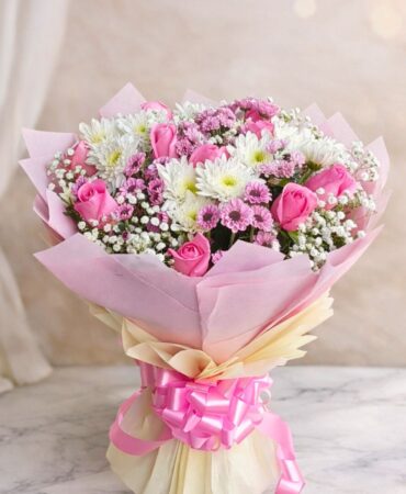 Pink rose and white chrysanthemum bouquet with baby’s breath wrapped in blush pink paper and satin ribbon.