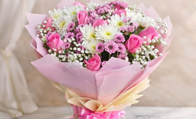 Pink rose and white chrysanthemum bouquet with baby’s breath wrapped in blush pink paper and satin ribbon.