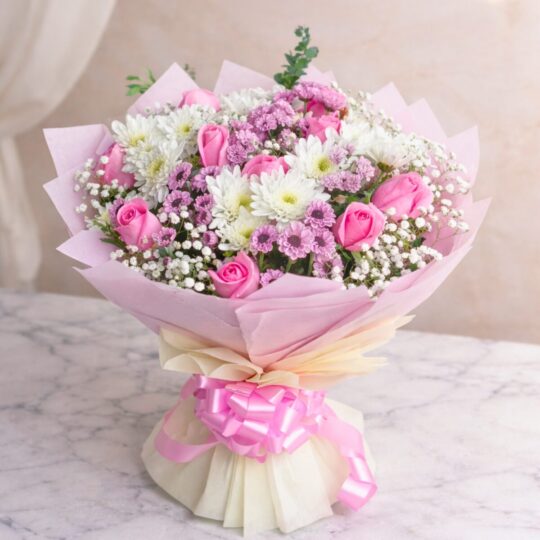 Pink rose and white chrysanthemum bouquet with baby’s breath wrapped in blush pink paper and satin ribbon.