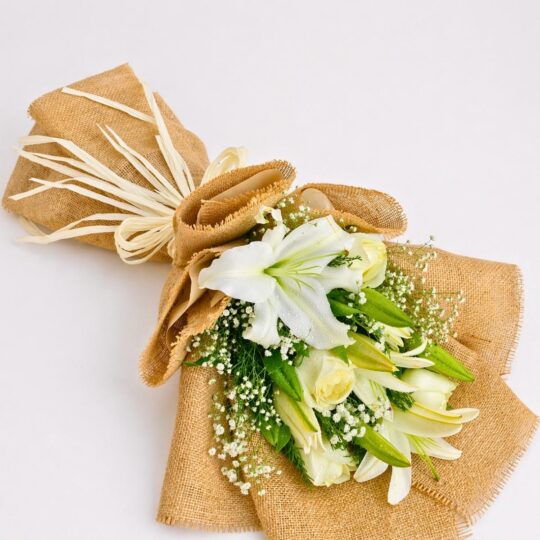Elegant white lily and rose bouquet with baby’s breath in burlap wrapping