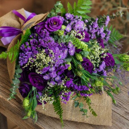 Luxury European style purple flower bouquet with lisianthus, asters, seasonal blooms and rustic wrapping by FreshKnots Bangalore. Available for online flowers delivery in Bangalore.