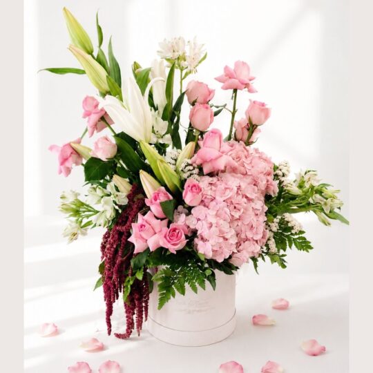 Premium blush pink flower arrangement with roses, hydrangea, white lilies, and fresh greens in a white box