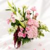 Premium blush pink flower arrangement with roses, hydrangea, white lilies, and fresh greens in a white box