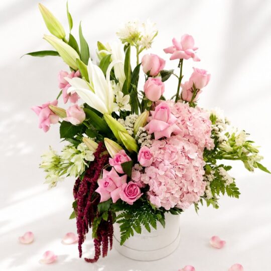 Premium blush pink flower arrangement with roses, hydrangea, white lilies, and fresh greens in a white box