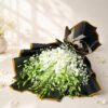 White orchid bouquet lying flat, black and gold wrap Bangalore
