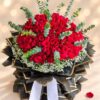 Close-up of tightly packed red roses with eucalyptus sprigs and a ring of white baby's breath