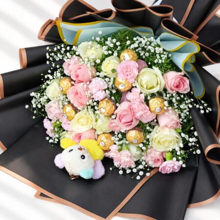 Pink and white roses with spray carnations and Ferrero Rocher in a black wrapped bouquet, top close-up
