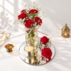 Red carnation centrepiece in Bangalore with carnations and baby's breath in a fairy light jar, a scented votive candle and a round mirror base