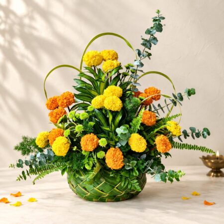 Diwali marigold table arrangement in Bangalore with yellow and orange marigolds, eucalyptus and ferns in a woven coconut leaf basket