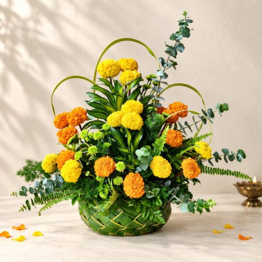 Diwali marigold table arrangement in Bangalore with yellow and orange marigolds, eucalyptus and ferns in a woven coconut leaf basket