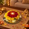 Top view of a marigold and red carnation urli arrangement with a floating tealight in a glass vase on a mirror