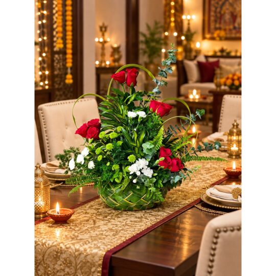 Red rose and carnation centrepiece in a woven leaf basket on a dining table runner, angled view